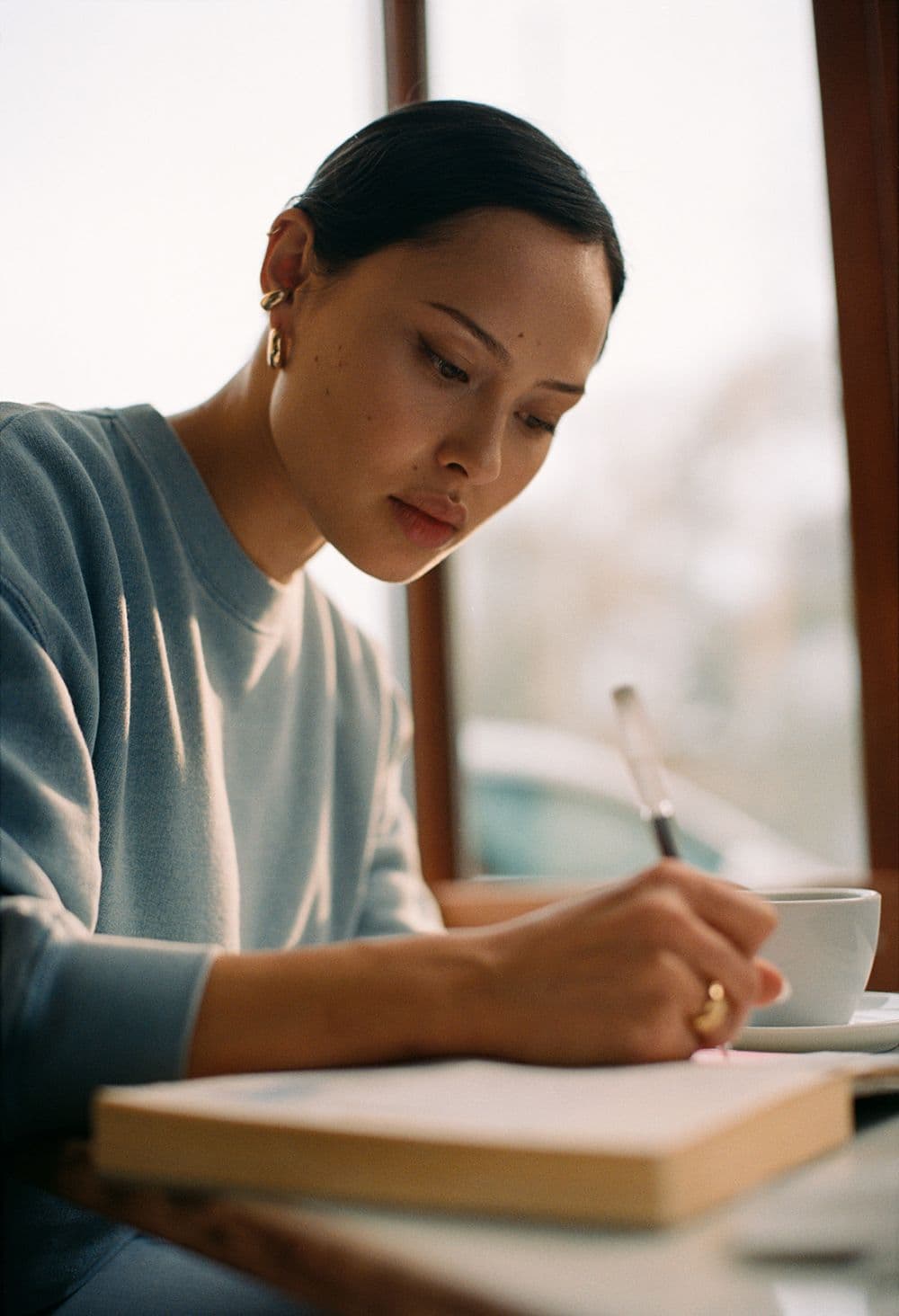 A woman in soft natural light, working on her laptop with quiet focus.